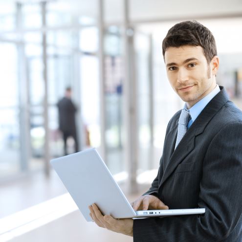 Young smiling businessman using laptop on corporate location, indoor.